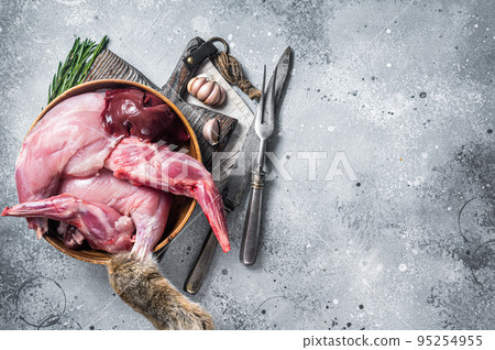 Raw hare game meat, legs and offals in wooden plate with herb. Gray background. Top view. Copy space Raw hare game meat, legs and offals in wooden plate with herb. Gray background. Top view. Copy space 95254955