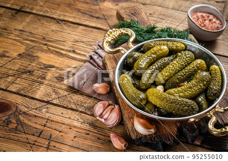Pickled gherkins cucumbers in bowl with herbs. Wooden background. Top view. Copy space Pickled gherkins cucumbers in bowl with herbs. Wooden background. Top view. Copy space 95255010