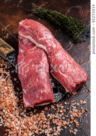 Uncooked lamb loin fillet, Mutton raw meat on butcher cleaver. Dark background. Top view Uncooked lamb loin fillet, Mutton raw meat on butcher cleaver. Dark background. Top view 95255014