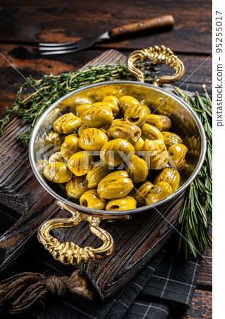 Turkish Grilled olives with olive oil and herbs in pan. Wooden background. Top view Turkish Grilled olives with olive oil and herbs in pan. Wooden background. Top view 95255017