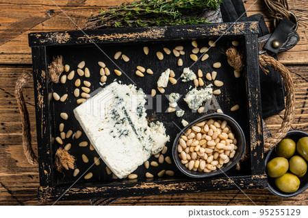 Gorgonzola cheese in a wooden tray with olives and nuts. Wooden background. Top view Gorgonzola cheese in a wooden tray with olives and nuts. Wooden background. Top view 95255129