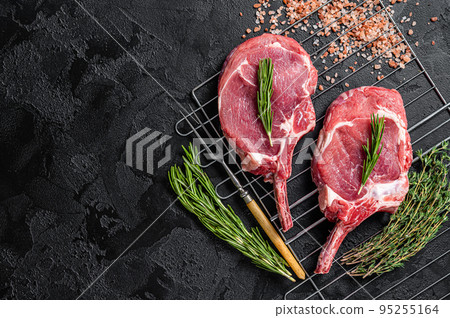 Fresh Raw Tomahawk rib eye beef steaks on grill. Black background. Top view. Copy space 95255164