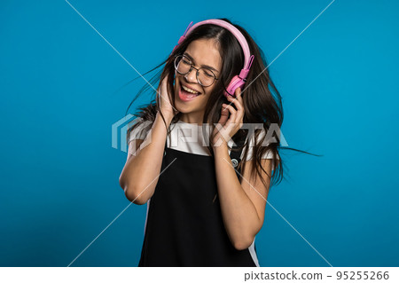 Pretty young asian girl with long hair having fun, smiling, dancing with headphones in studio Pretty young asian girl with long hair having fun, smiling, dancing with headphones in studio 95255266