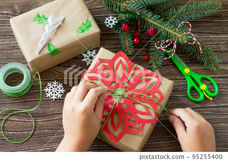 A child is holding Packing presents for Christmas. Handmade. Project of children's creativity, handicrafts, crafts for kids. 95255400
