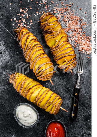 Roasted Tornado or twisted potatoes with ketchup sauce. Black background. Top view Roasted Tornado or twisted potatoes with ketchup sauce. Black background. Top view 95255492