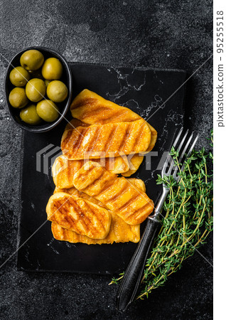 Griiled Halloumi cheese on marble board with herbs. Black background. Top view 95255518