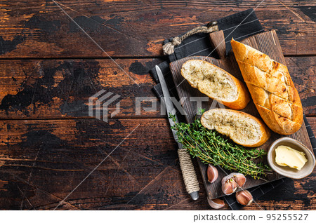 Toasted Garlic bread with herbs and butter on wooden cutting board. Wooden background. Top view. Copy space 95255527