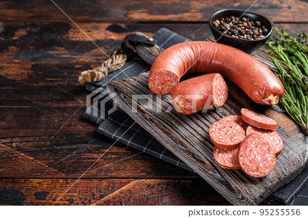 Sliced Sucuk beef meat sausage on a cutting board with herbs. Wooden background. Top view. Copy space 95255556