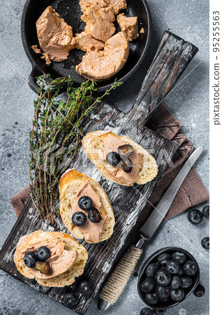 Toast with Foie gras pate and fresh blueberry on wooden board. Gray background. Top view Toast with Foie gras pate and fresh blueberry on wooden board. Gray background. Top view 95255563