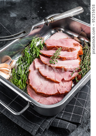 Homemade Smoked pork ham meat in steel trey with thyme and rosemary. Black background. Top view. Copy space 95255658