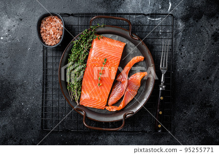 Slices of lightly salted salmon with thyme in a steel tray. Black background. Top view Slices of lightly salted salmon with thyme in a steel tray. Black background. Top view 95255771