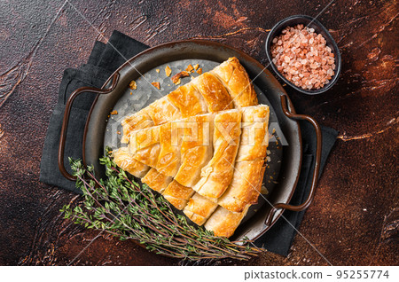 Slices of baked Round Borek cheese pie in kitchen tray with herbs. Dark background. Top view Slices of baked Round Borek cheese pie in kitchen tray with herbs. Dark background. Top view 95255774
