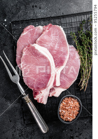 Raw pork cutlet chop steak for fry on pan with herbs. Black background. Top view Raw pork cutlet chop steak for fry on pan with herbs. Black background. Top view 95255794
