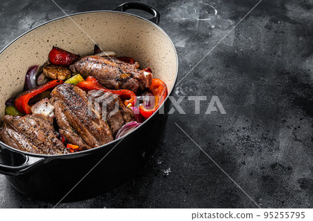 Braised slow cooked lamb shank in red wine sauce with vegetables in cooking pot. Black background. Top view. Copy space Braised slow cooked lamb shank in red wine sauce with vegetables in cooking pot. Black background. Top view. Copy space 95255795