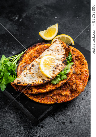 Lahmacun traditional Turkish pizza and wraps with salad on marble board with spices. Black background. Top view Lahmacun traditional Turkish pizza and wraps with salad on marble board with spices. Black background. Top view 95255806
