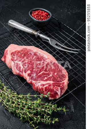 Raw striploin or New York beef meat steak ready for BBQ. Black background. Top view 95255858