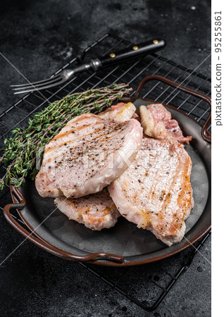 Grilled delicious pork chop steaks with herbs and spices. Black background. Top view 95255861