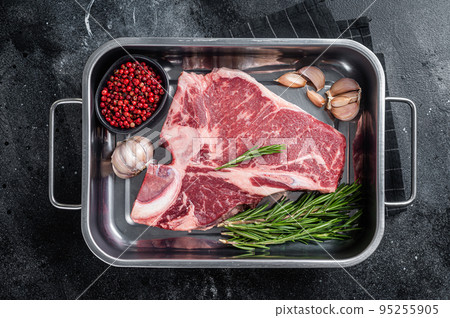 Fresh Raw porterhouse T bone beef meat Steak in steel tray with herbs. Black background. Top view 95255905