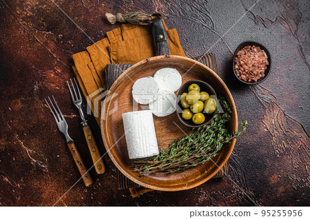 Soft Goat cheese chevre in a plate with thyme and olives. Dark background. Top view Soft Goat cheese chevre in a plate with thyme and olives. Dark background. Top view 95255956
