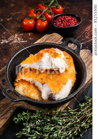 Roasted tilapia fillet in a skillet with breadcrumbs. Dark background. Top view 95255990
