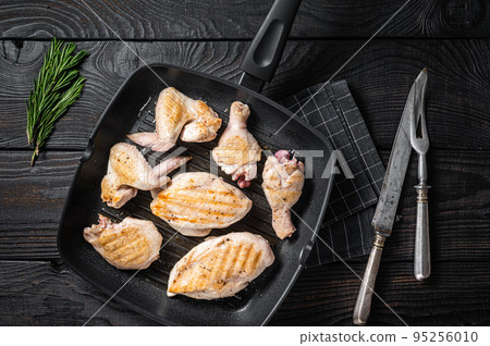 Roasted on a grill skillet chicken meat and chicken parts - drumstick, breast fillet, wing, thigh. Black wooden background. Top view Roasted on a grill skillet chicken meat and chicken parts - drumstick, breast fillet, wing, thigh. Black wooden background. Top view 95256010