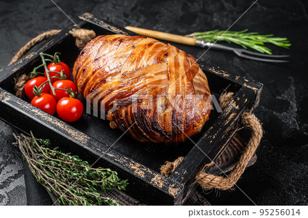 Roast bacon wrapped meatloaf, meat loaf in a tray with herbs. Black background. Top view Roast bacon wrapped meatloaf, meat loaf in a tray with herbs. Black background. Top view 95256014