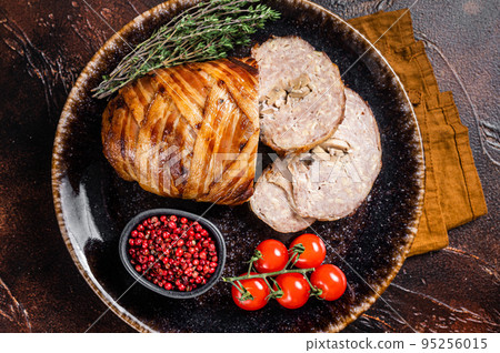 Baked delicious beef meatloaf, sliced meat loaf with bacon and herbs on a plate. Dark background. Top view 95256015