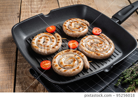 Fried on a grill pan spiral meat sausages with spices. Wooden background. Top view Fried on a grill pan spiral meat sausages with spices. Wooden background. Top view 95256018