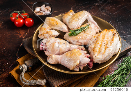 Assortment of Roast chicken meat parts on a plate. Drumstick, breast fillet, wing, thigh. Dark background. Top view 95256046