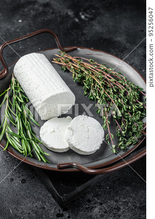 Chevre goat soft cheese with herbs on a tray. Black background. Top view Chevre goat soft cheese with herbs on a tray. Black background. Top view 95256047
