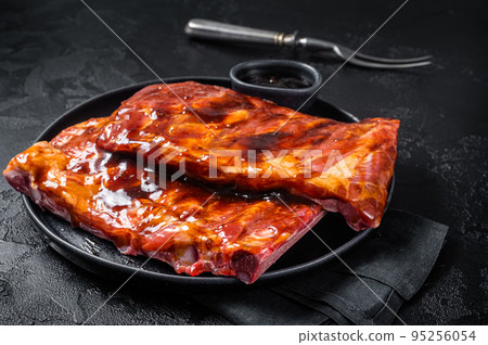 Ready for BBQ raw pork spare ribs with barbecue sauce. Black background. Top view Ready for BBQ raw pork spare ribs with barbecue sauce. Black background. Top view 95256054