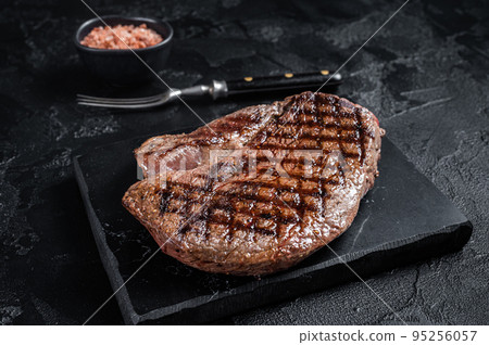 Grilled top sirloin or rump steak on a marble board. Black background. Top view 95256057