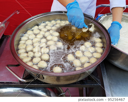 Cooking fry curd balls in boiling hot oil 95256467