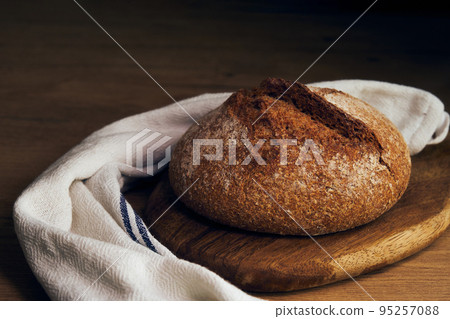 a loaf of bread on a wooden board 95257088