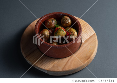 roasted potatoes with herbs and spice in clay bowl on black background roasted potatoes with herbs and spice in clay bowl on black background 95257134