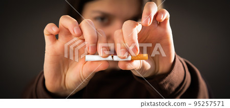 Girl breaks a cigarette in her hands, view closeup. Girl breaks a cigarette in her hands, view closeup. 95257571