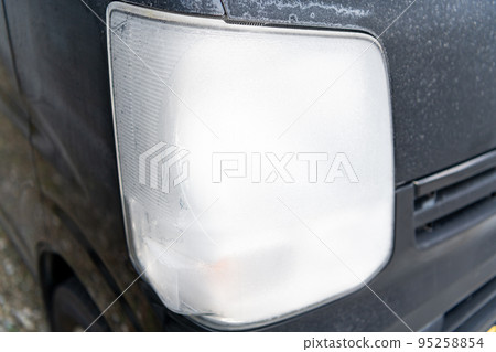 The headlights of a car that has become pure white due to frost in the winter 95258854