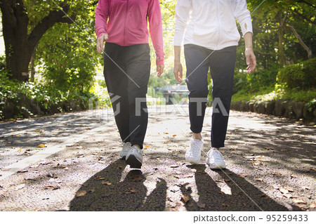 Feet of two middle-aged women walking 95259433
