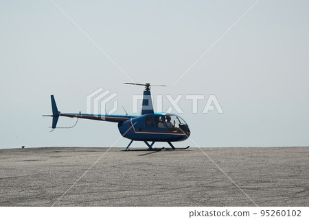 Blue helicopter flying in grey cloudy skies Blue helicopter flying in grey cloudy skies 95260102