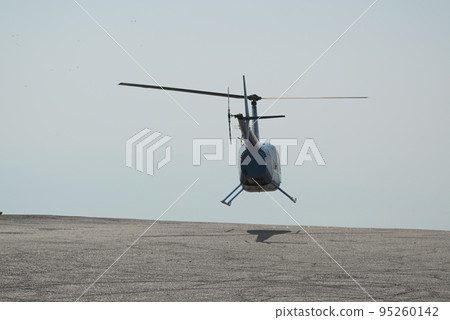 Blue helicopter flying in grey cloudy skies Blue helicopter flying in grey cloudy skies 95260142