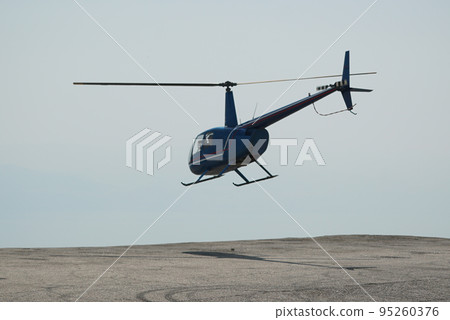 Blue helicopter flying in grey cloudy skies Blue helicopter flying in grey cloudy skies 95260376