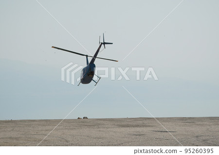 Blue helicopter flying in grey cloudy skies Blue helicopter flying in grey cloudy skies 95260395