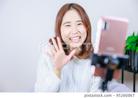 對著手機攝像頭微笑和揮手的女人 95260867