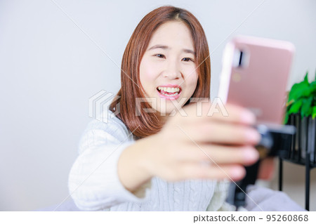 一位女士正在操作連接在自拍杆上的手機 一位女士正在操作連接在自拍杆上的手機 95260868