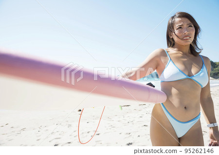 手持衝浪板的年輕女子。根據我們的使用條款，請勿將其用於成人或其他負面形象。 95262146