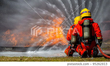 Asian firefighter on duty firefighting, Asian fireman spraying high pressure water, Fireman in fire fighting equipment uniform spray water from hose for fire fighting. Asian firefighter on duty firefighting, Asian fireman spraying high pressure water, Fireman in fire fighting equipment uniform spray water from hose for fire fighting. 95262813