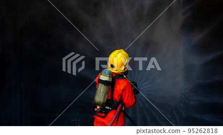 Asian firefighter on duty firefighting, Asian fireman spraying high pressure water, Fireman in fire fighting equipment uniform spray water from hose for fire fighting. 95262818