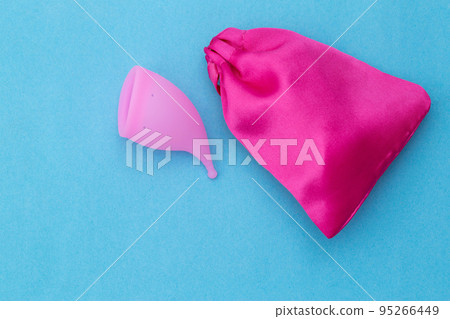 Pink menstrual cup and cover on a light blue background. Modern development in gynecology for collecting discharge during menstruation from a girl. Copy space for text 95266449