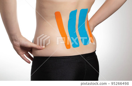 Kinesiological tape orange and blue on the back of the lumbar spine of the girl. Taping problem areas and pain relief 95266498