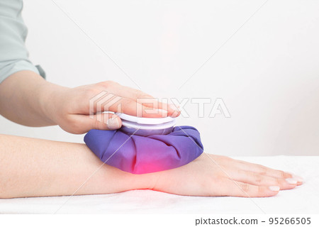 A girl applies a cooling bag of ice to the wrist joint on her arm during sprains and trauma. Eliminate pain and inflammation, arthritis 95266505